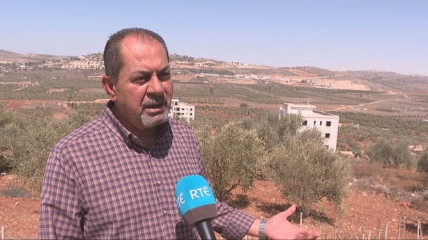 Yasser Alkam stands on a sandy hill in the West Bank.
