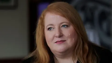 PA Media Naomi Long who has long light red hair and is wearing a black top and jacket.