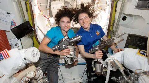 NASA NASA astronauts Jessica Meir (left) and Christina Koch are inside the Quest airlock preparing the U.S. spacesuits and tools they will use on their first spacewalk together.
