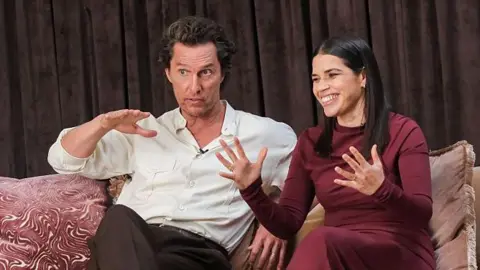 Getty Images Matthew McConaughey and America Ferrera in conversation on a sofa in smart casual clothes