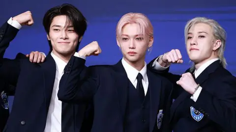 Getty Images Stray Kids members I.N, Felix and Bang Chan celebrate the launch of their fourth full-length album, Karma, at a press conference in Seoul, August 2025