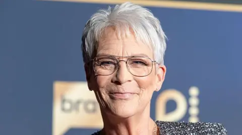 Getty Images Jamie Lee Curtis smiling, it's a close-up head shot and she has short, grey hair and glasses
