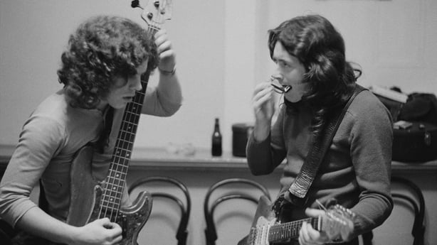 Irish singer and guitarist Rory Gallagher (1948-1995) with his Fender Stratocaster strapped on, plays a harmonica backstage with bass guitarist Gerry McAvoy prior to a concert at Leeds City Hall in Leeds, England on 25th March 1972. (Photo by Michael Putland/Getty Images)